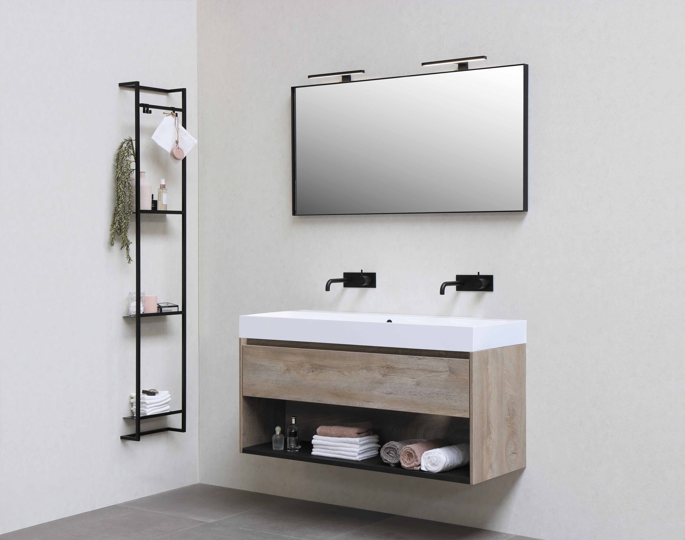 Moderne zariadená kúpelňa v minimalistickom štýle s drevenou závesnou skrinkou s dvoma umývadlami a so zrkadlom a kovovou regálovou policou s doplnkami ako napríklad šampóny a uteráky